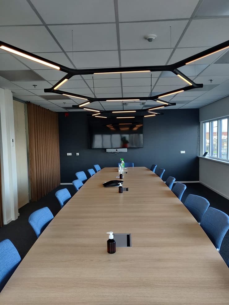 Directiekamer met lange vergadertafel en zeshoekige ledverlichting