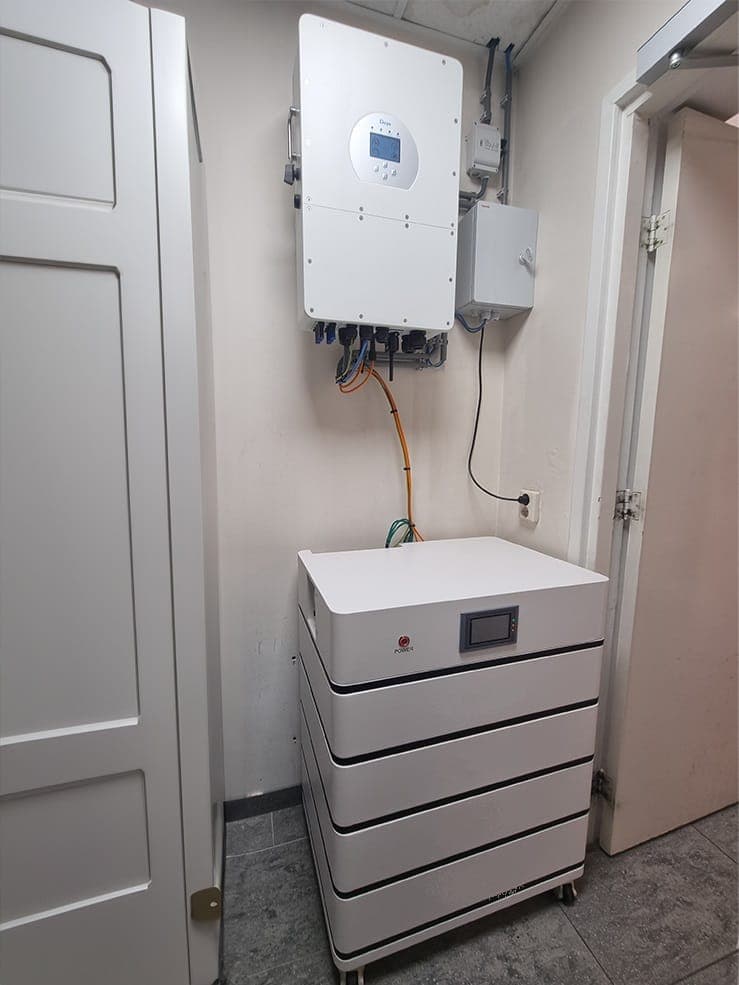 Deye energieopslagsysteem met omvormer aan de wand en gestapelde batterijmodules eronder