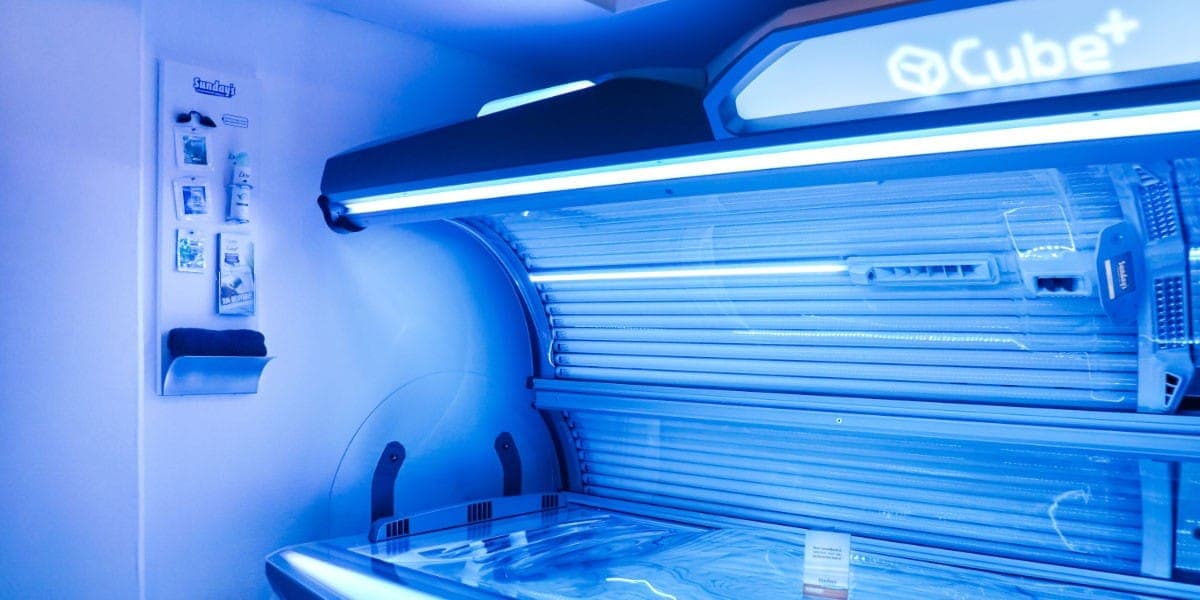 Cube+ zonnebank met blauwe verlichting in een cabine van de zonnestudio