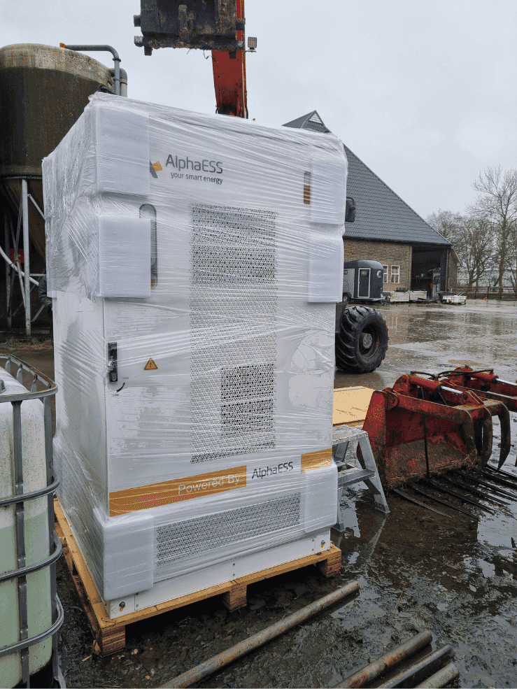 Aankomst van de Alpha ESS batterij in verpakking op het natte erf van de melkveehouderij
