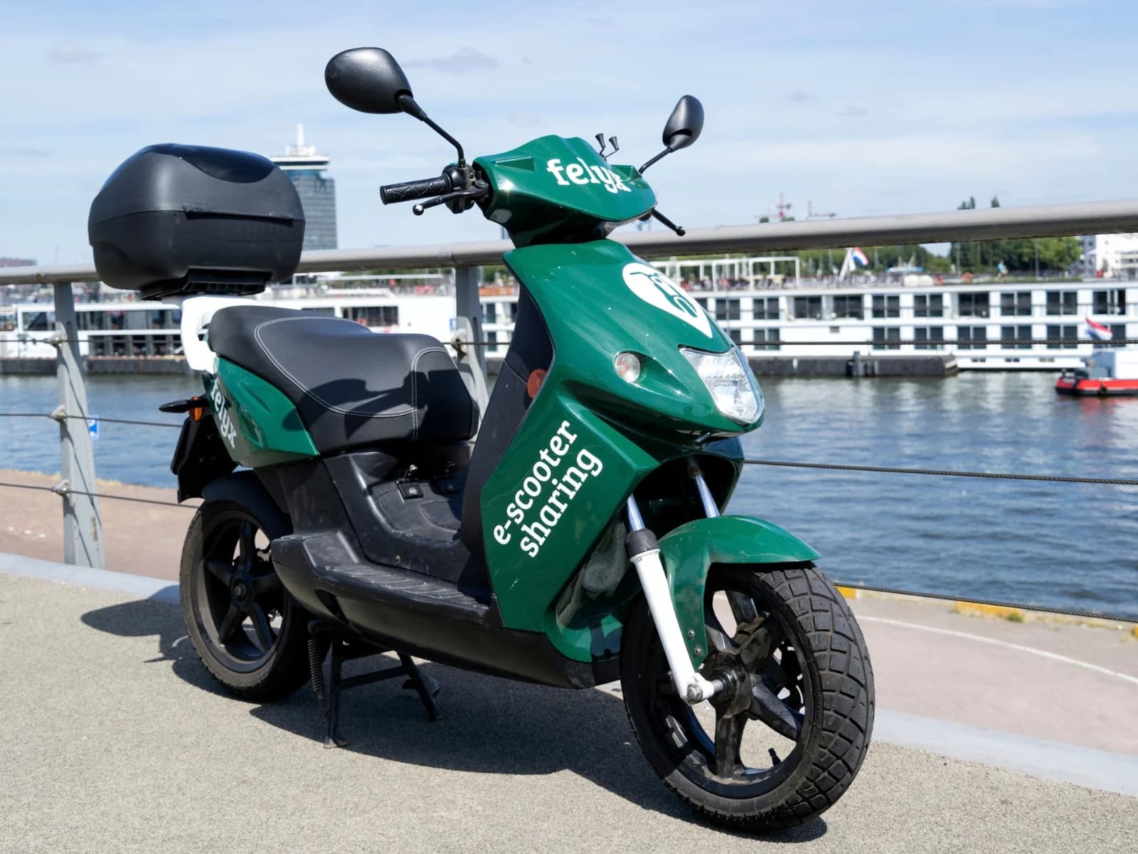 Groene elektrische deelscooter van Felyx geparkeerd aan een kade