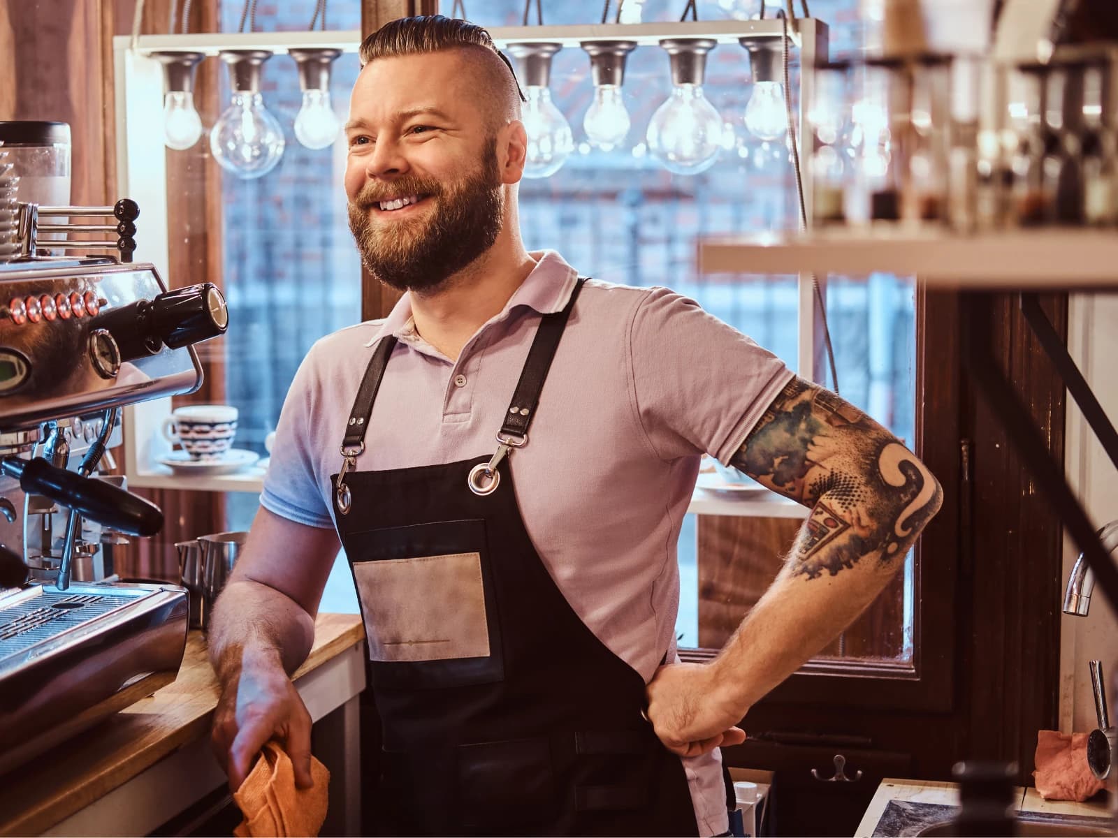 Lachende barista met schort achter de espressomachine in een café