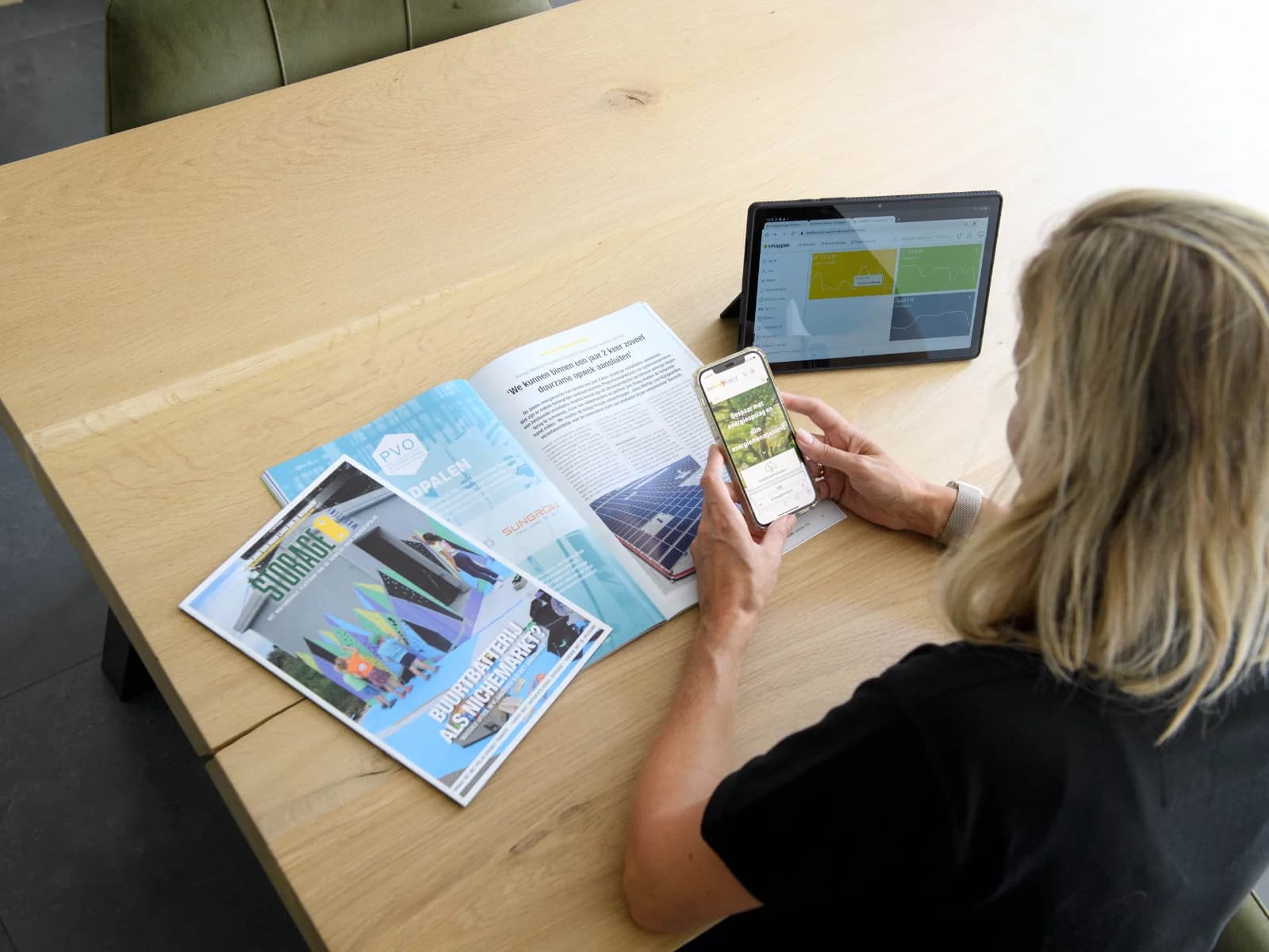 Aan tafel met een tijdschrift, een tablet en een smartphone met nieuws over slimme energie
