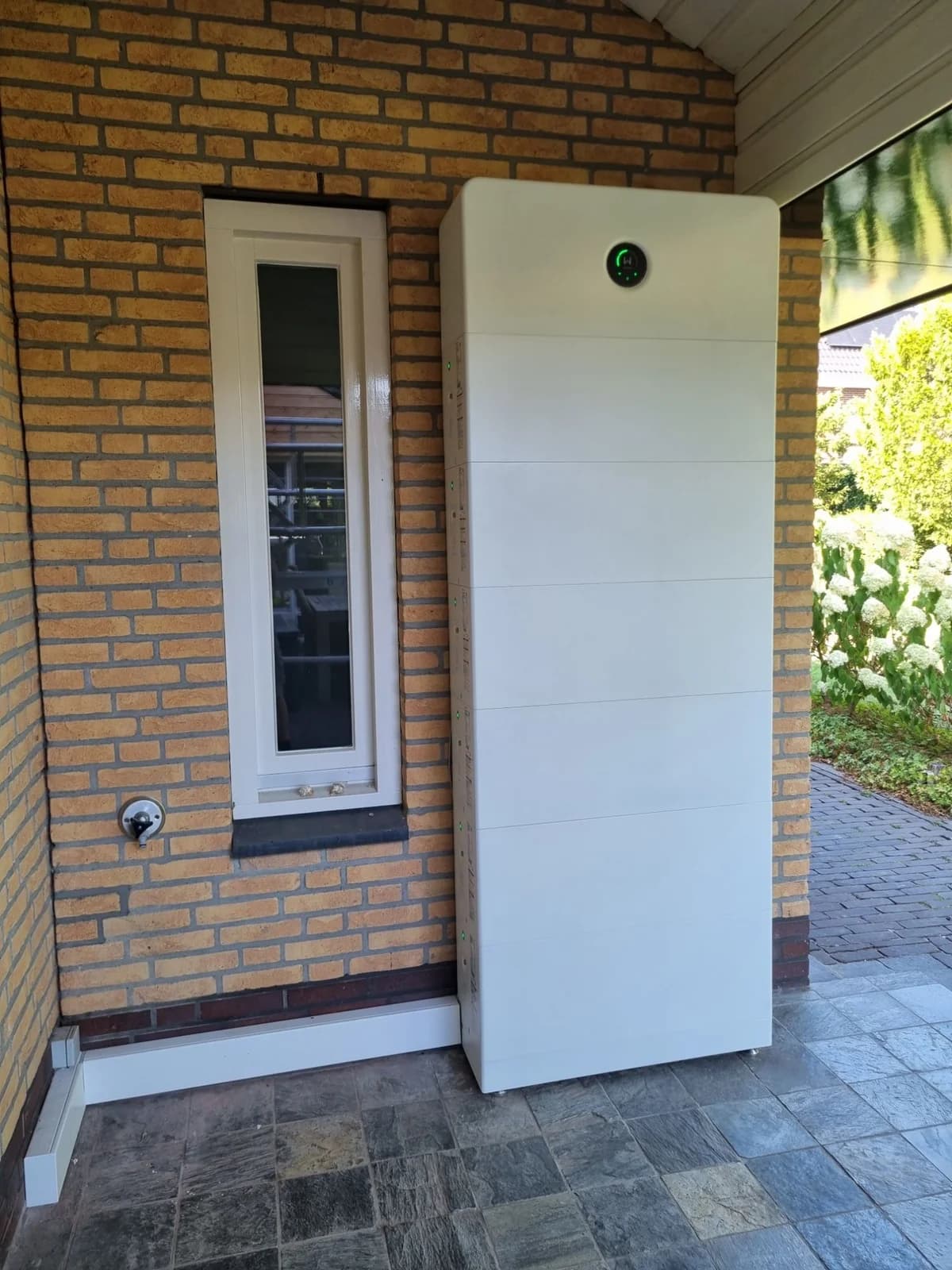 Vooraanzicht van het GoodWe ESA batterijsysteem onder het afdak, met het statuslampje bovenaan