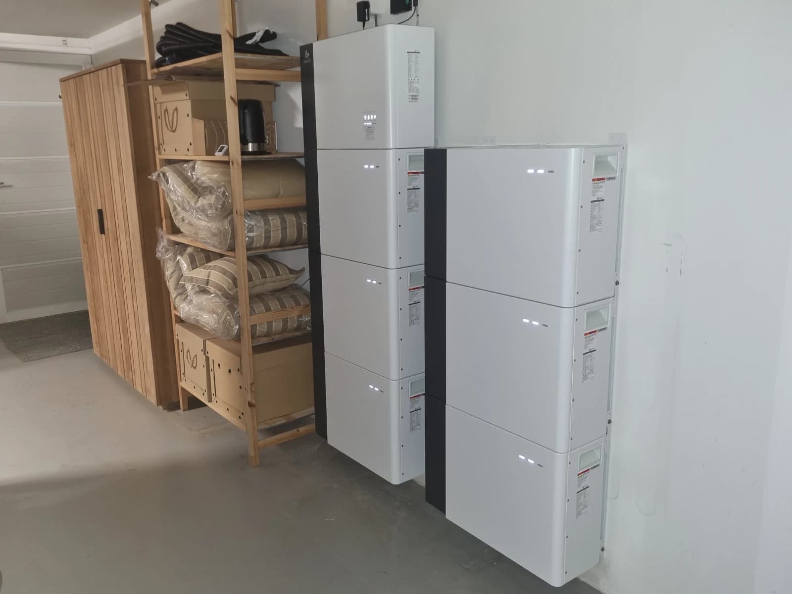 Twee Alpha ESS Smile-thuisbatterijen met gestapelde batterijmodules aan de muur van een garage
